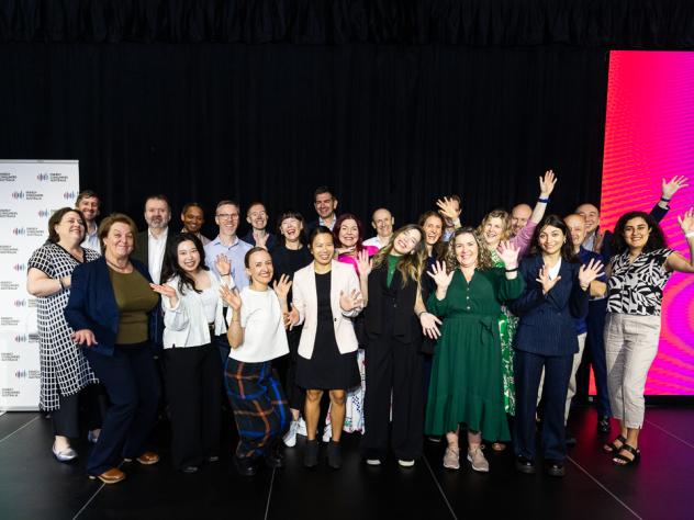 Photo of the ECA team at Foresighting Forum 2026. The team is standing on stage in front of a black curtain, waving and smiling.