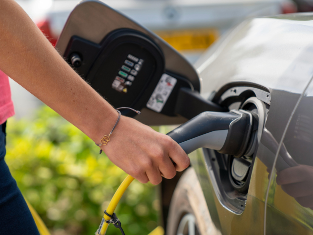 Close-up photo of a hand plugging an electric vehicle (EV) charger into an EV