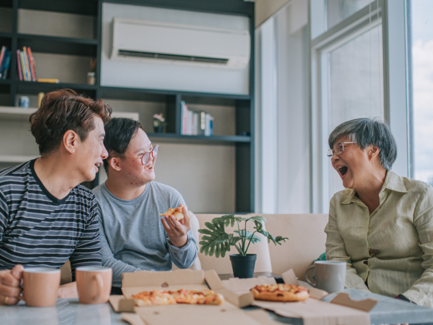 Photo of people enjoying pizza sitting in front of an air conditioner in an apartment