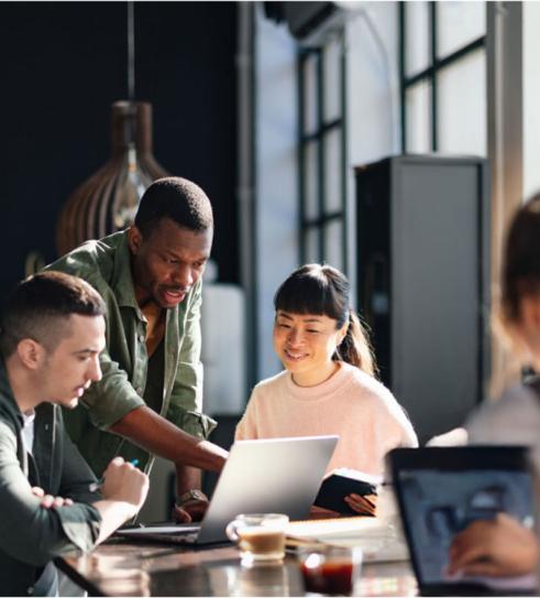 Group of people sitting at a table working on laptops