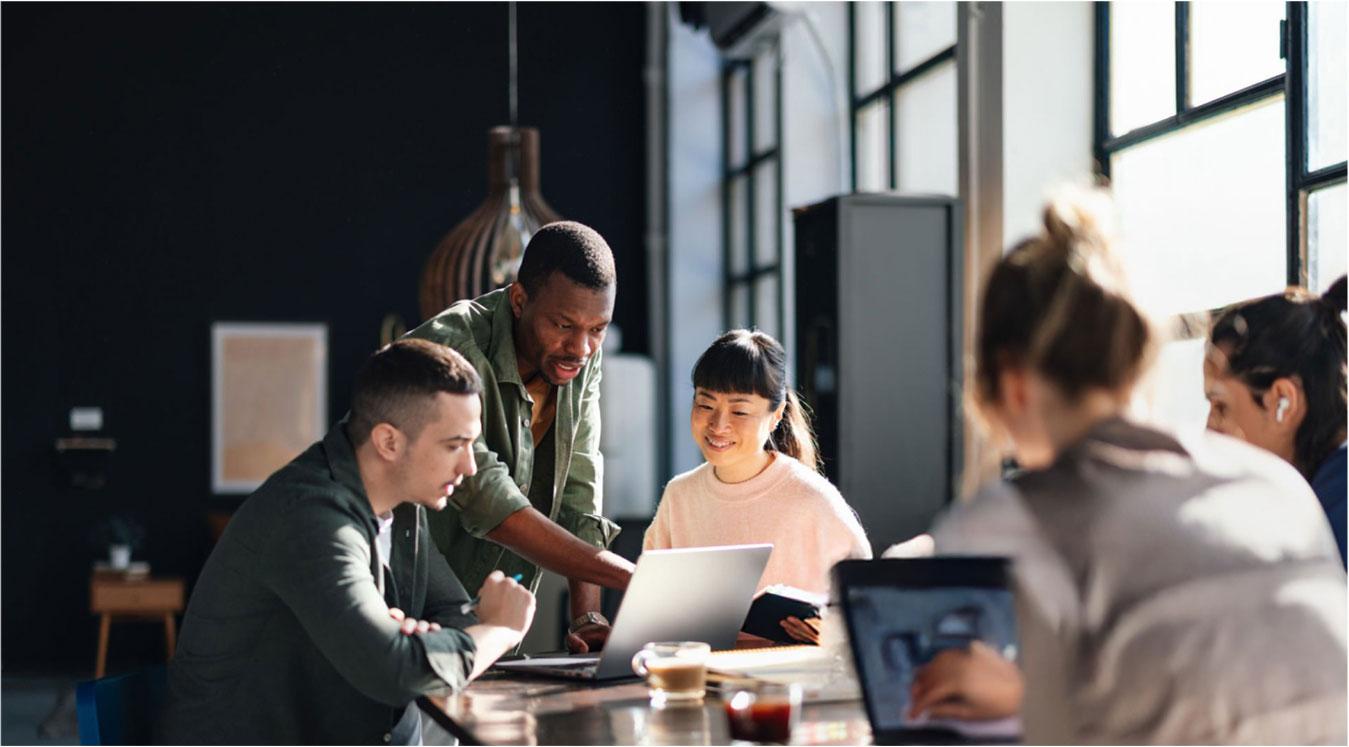 Group of people sitting at a table working on laptops