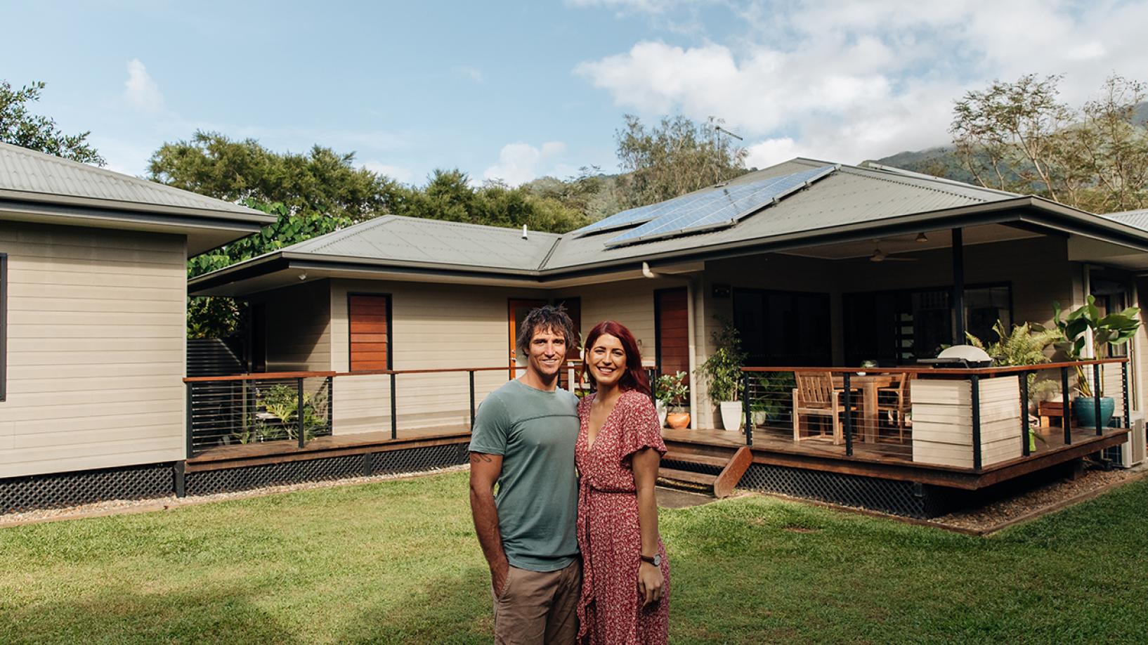 Couple standing in front of home with solar panels