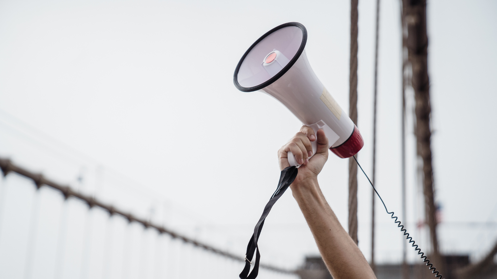 Photo of a hand holding a megaphone in the air.