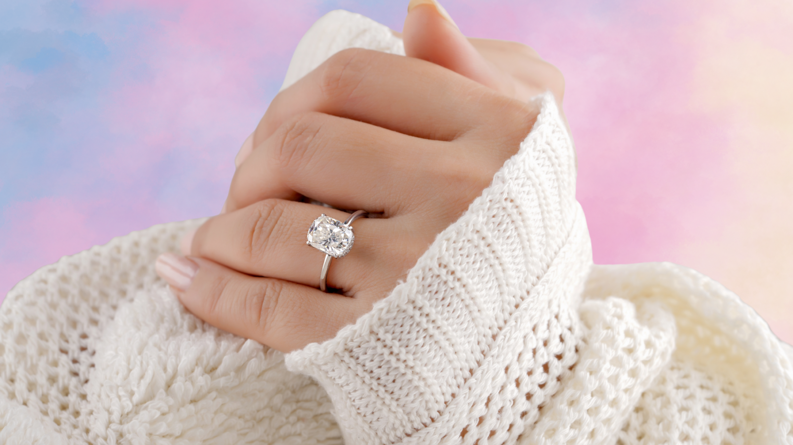 Photo of a pair of hands in a cream coloured jumper with a rainbow background