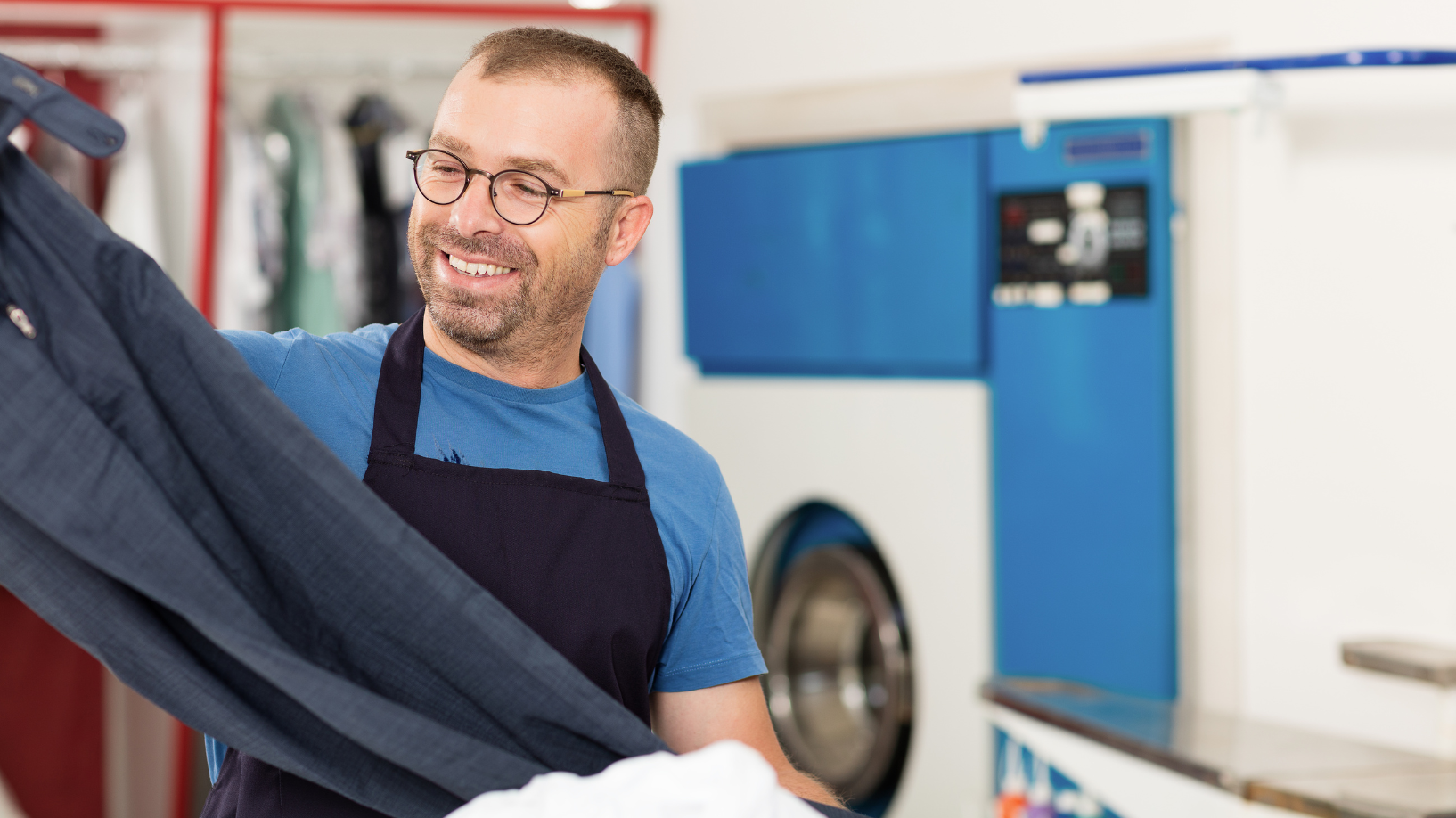 Man working in a laundromat and looking at some pants