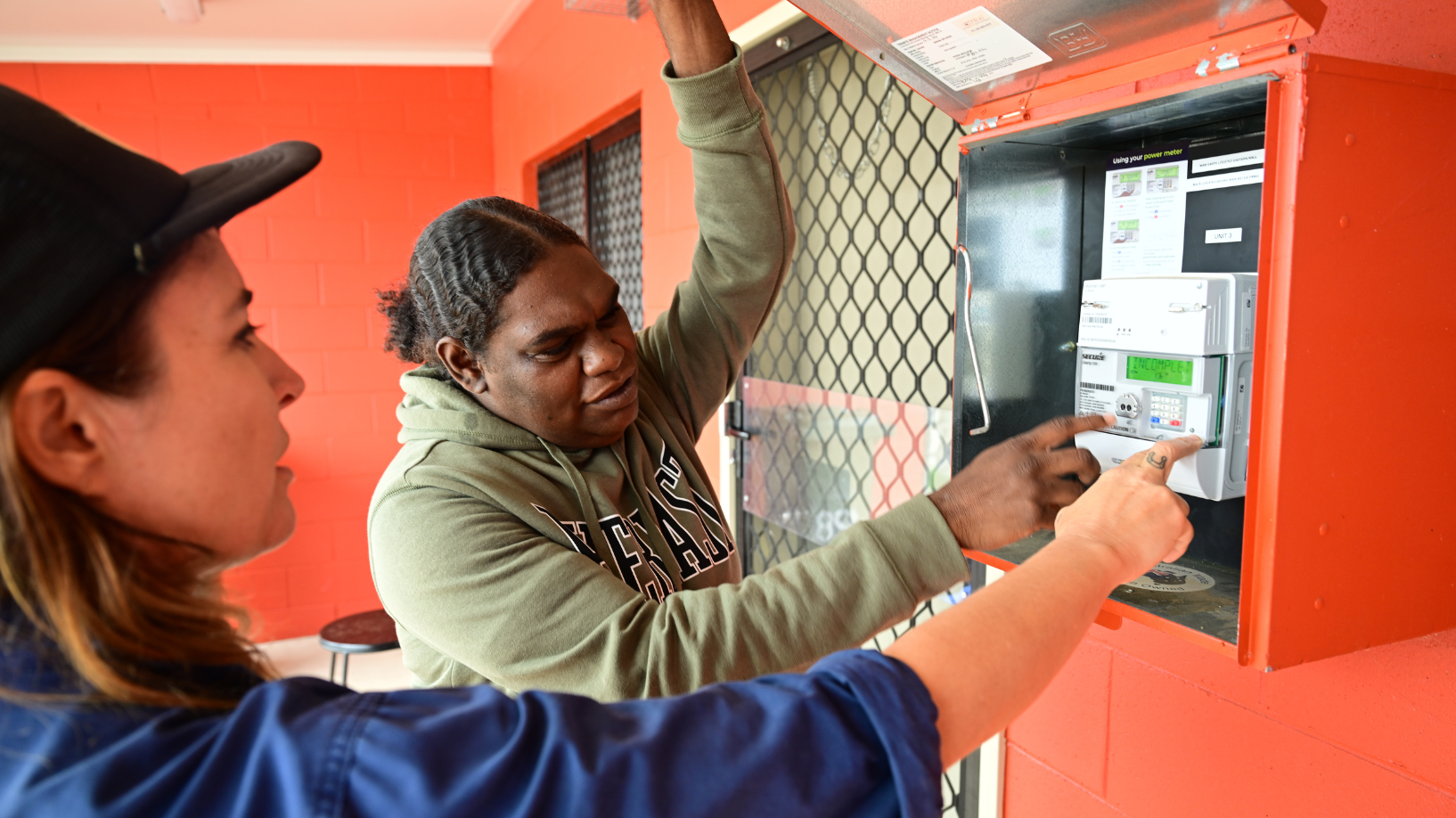 Two people look at a prepayment meter