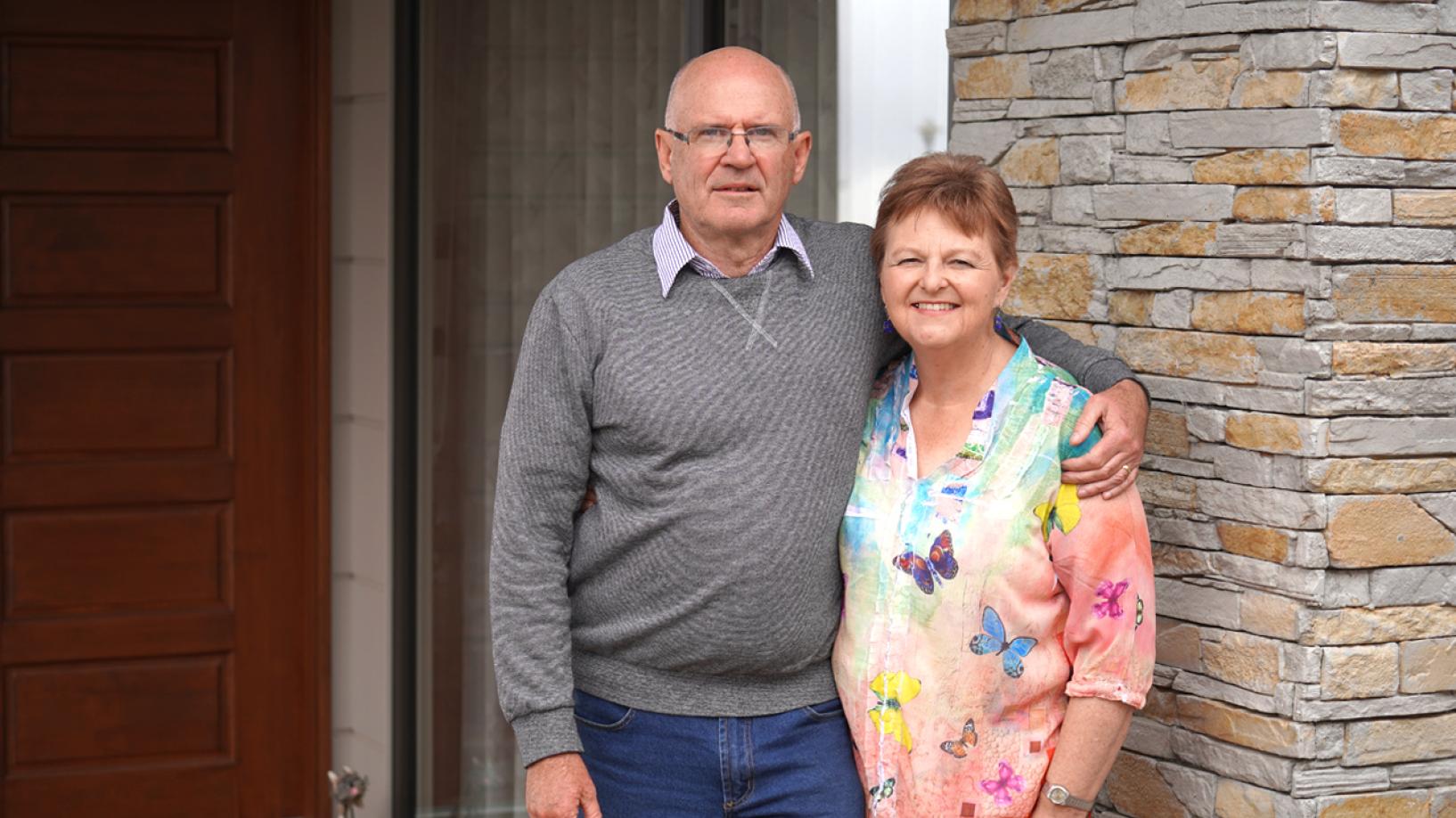 Older man and woman standing outside their home front door