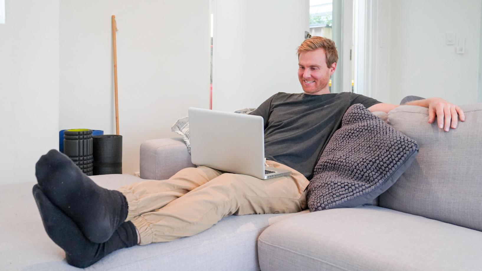 Man sitting on couch looking at laptop
