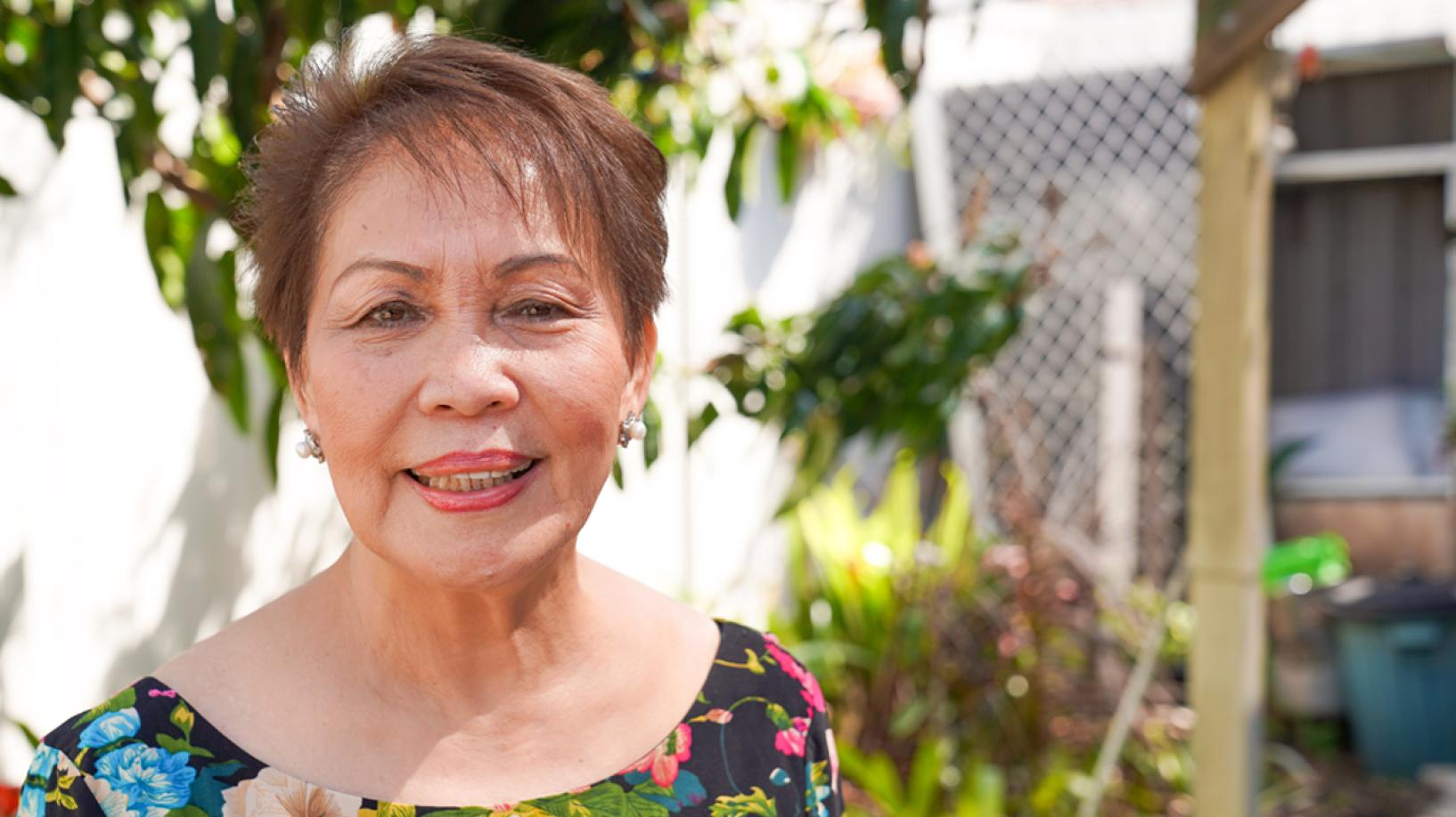 Older woman standing in her garden smiling at camera