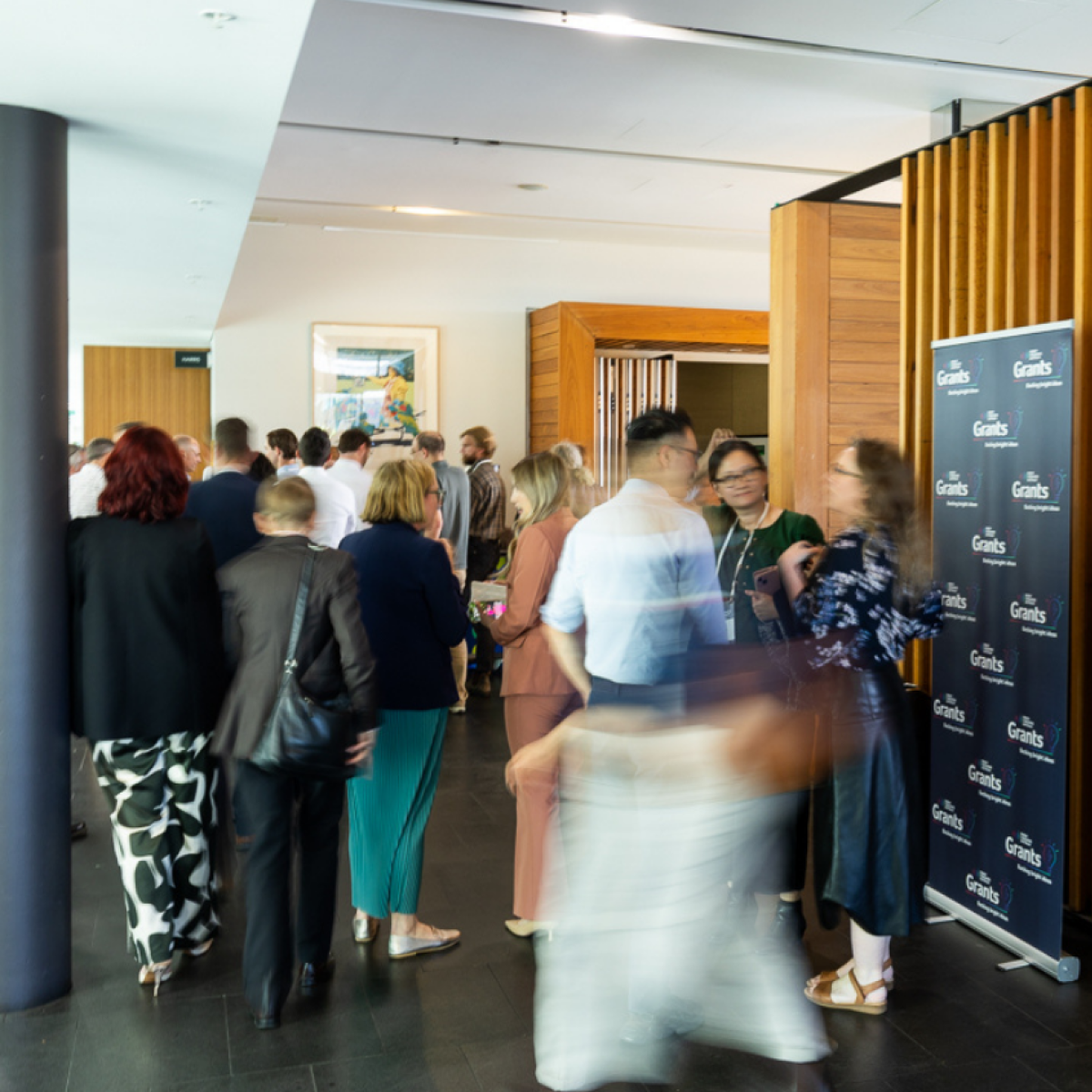 Photo of blurry people standing near the entrance to the 2025 Foresighting Forum