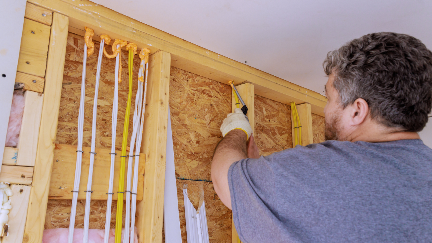 A man is installing insulation into a wall. 