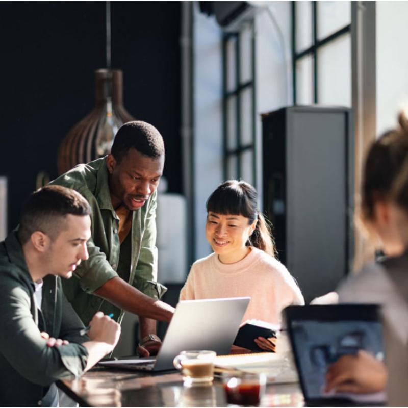 Group of people sitting at a table working on laptops