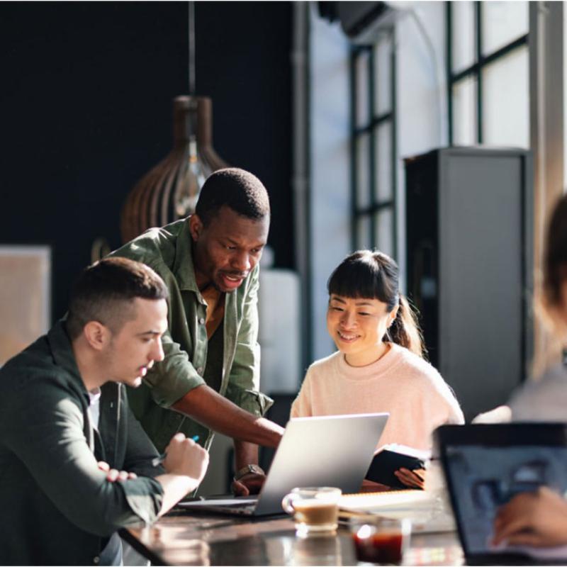 Group of people sitting at a table working on laptops