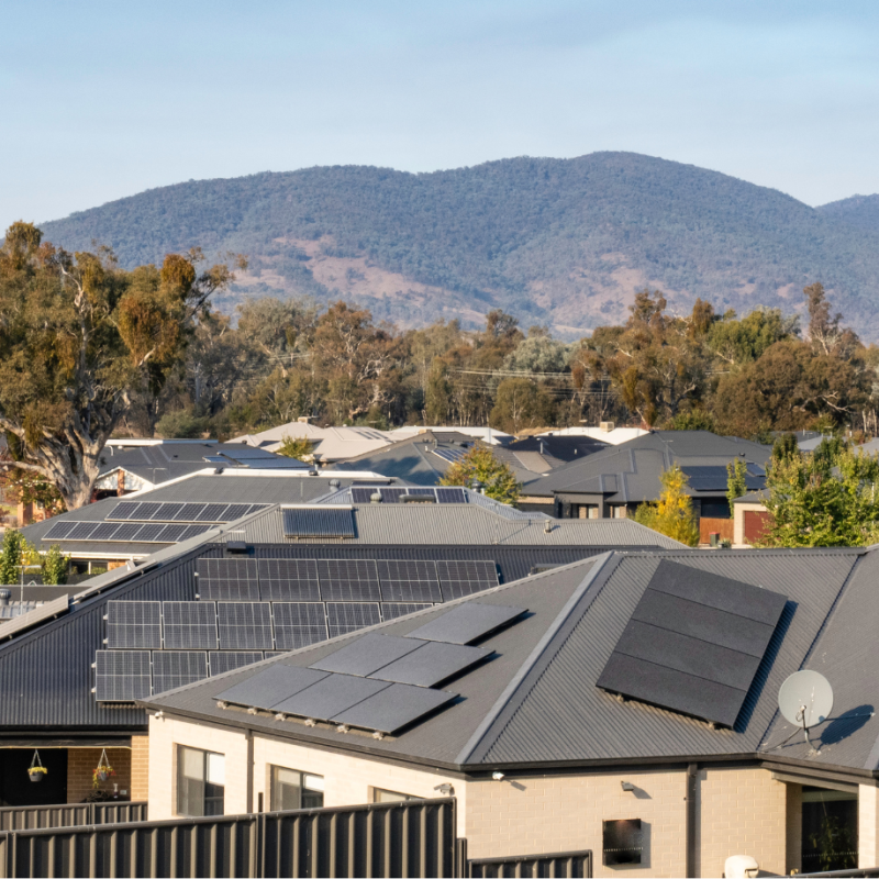 Photo of rooftops in Wodonga, with solar panels and surrounded by rolling green hills and gum trees.