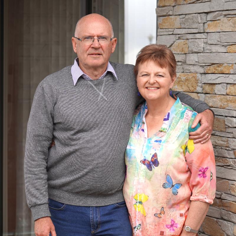 Older man and woman standing outside their home front door