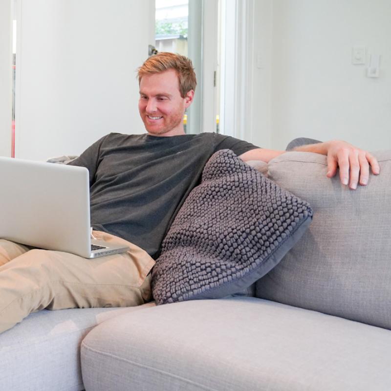 Man sitting on couch looking at laptop