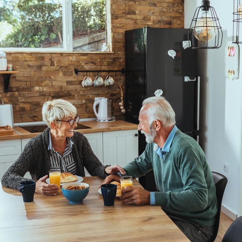 Photo of two people sitting a table over breakfast, smiling at each other