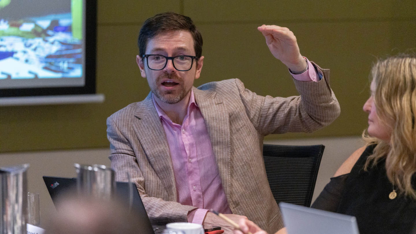 Photo of a person speaking while gesticulating with their hands positioned as if to show how high something is