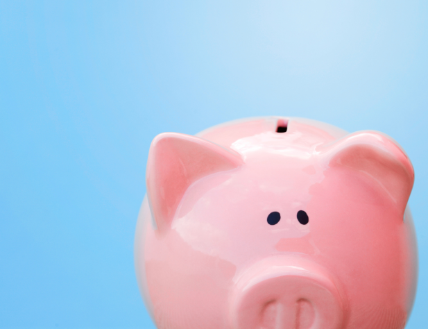 Close-up photo of a pink piggy bank slightly out of frame, against a bright blue background