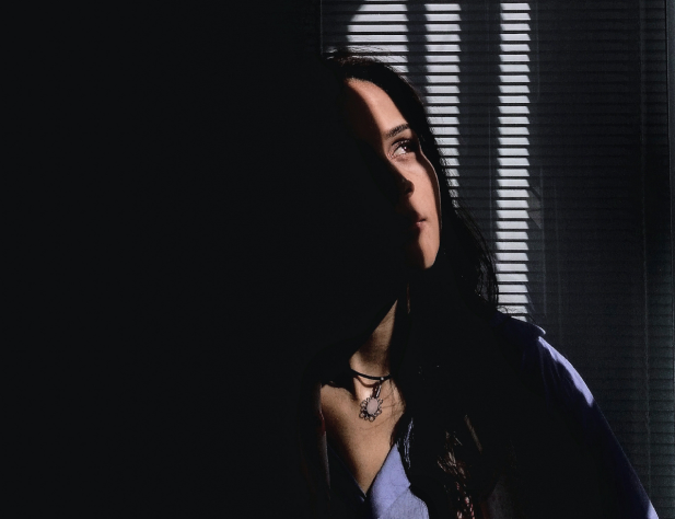 Image of a person shrouded in partial darkness. You can see part of their face, looking up into the light.