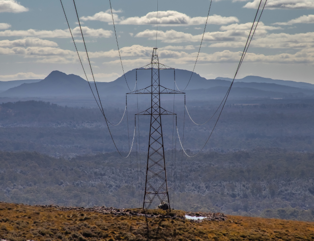 Photo of a transmission line with an Australian landscape and clouds in the background.