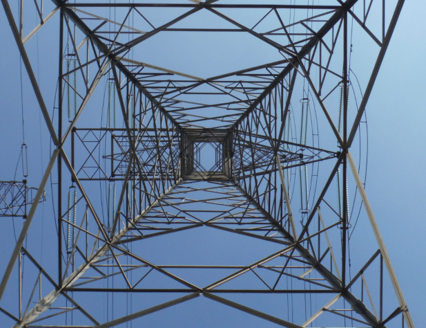 Photo of a transmission tower from underneath, looking up towards a blue sky.