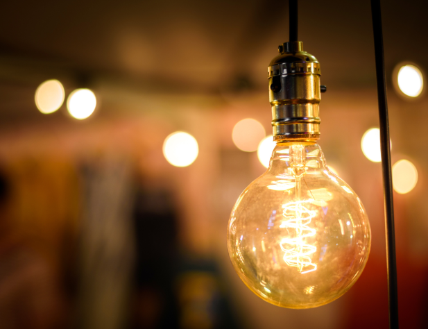Close-up photo of an illuminated festoon light bulb, with other light bulbs glowing and out of focus in the background.