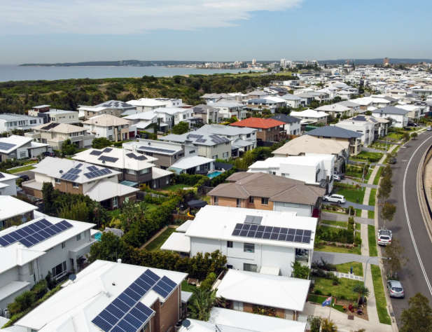 Aerial photo of houses with lots of white roofs, and solar panels on top.