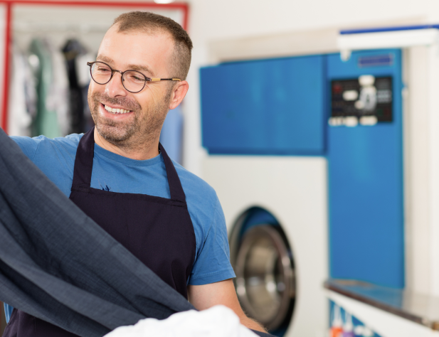 Man working in a laundromat and looking at some pants