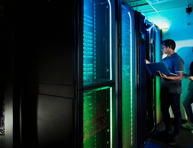 Photo of two technicians standing in a dark room with servers in a data centre