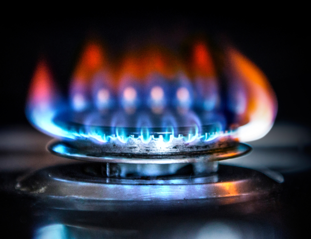 Close-up photo of a gas burner stove with blue and orange flame