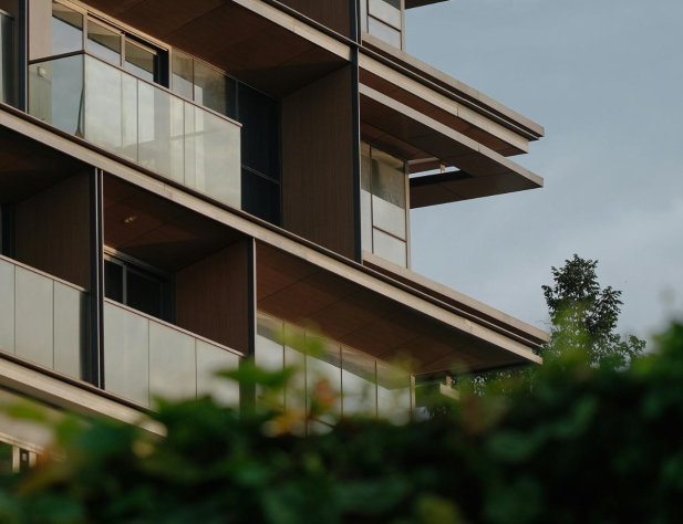 Photo of an apartment block from behind a hedge