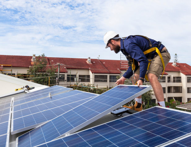 Photo of an electrician installing solar panels on a rooftop.