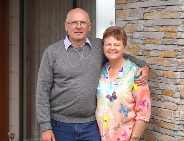 Older man and woman standing outside their home front door
