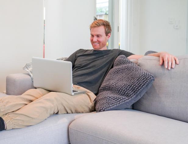 Man sitting on couch looking at laptop