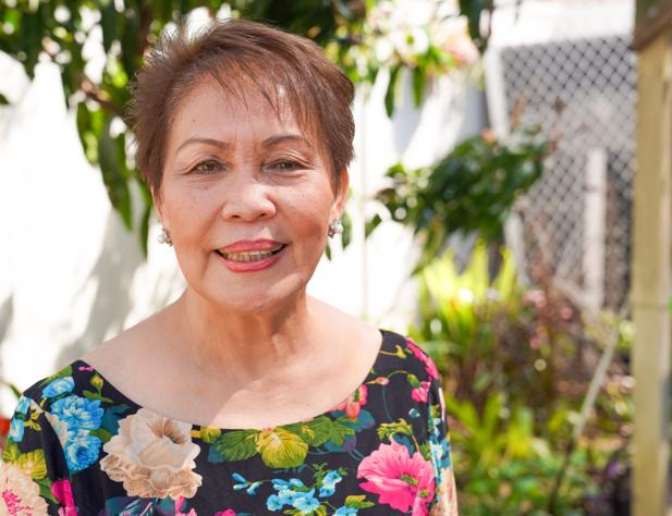 Older woman standing in her garden smiling at camera