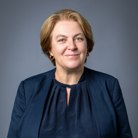 Photo of person in navy top and blazer, looking at camera, smiling