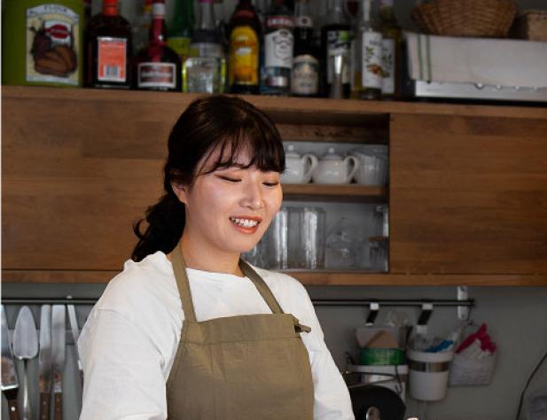 Young woman cutting cake in shop