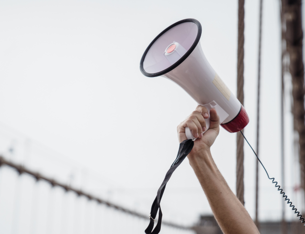 Photo of a hand holding a megaphone in the air.