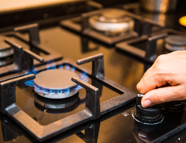 Photo of a hand turning a knob on a gas cooktop