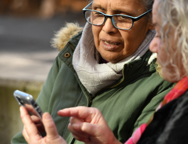 Photo of two people looking at a mobile one. One of them is pointing at it.