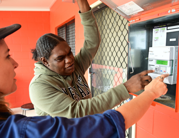 Two people look at a prepayment meter