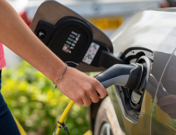 Close-up photo of a hand plugging an electric vehicle (EV) charger into an EV