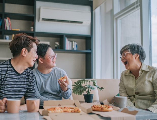 Photo of people enjoying pizza sitting in front of an air conditioner in an apartment