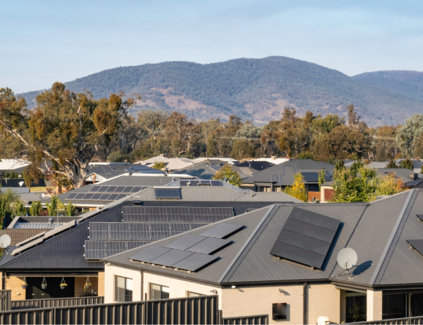 Photo of rooftops in Wodonga, with solar panels and surrounded by rolling green hills and gum trees.
