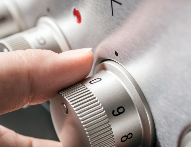 Close-up photo of a hand adjusting a stove hob to zero.