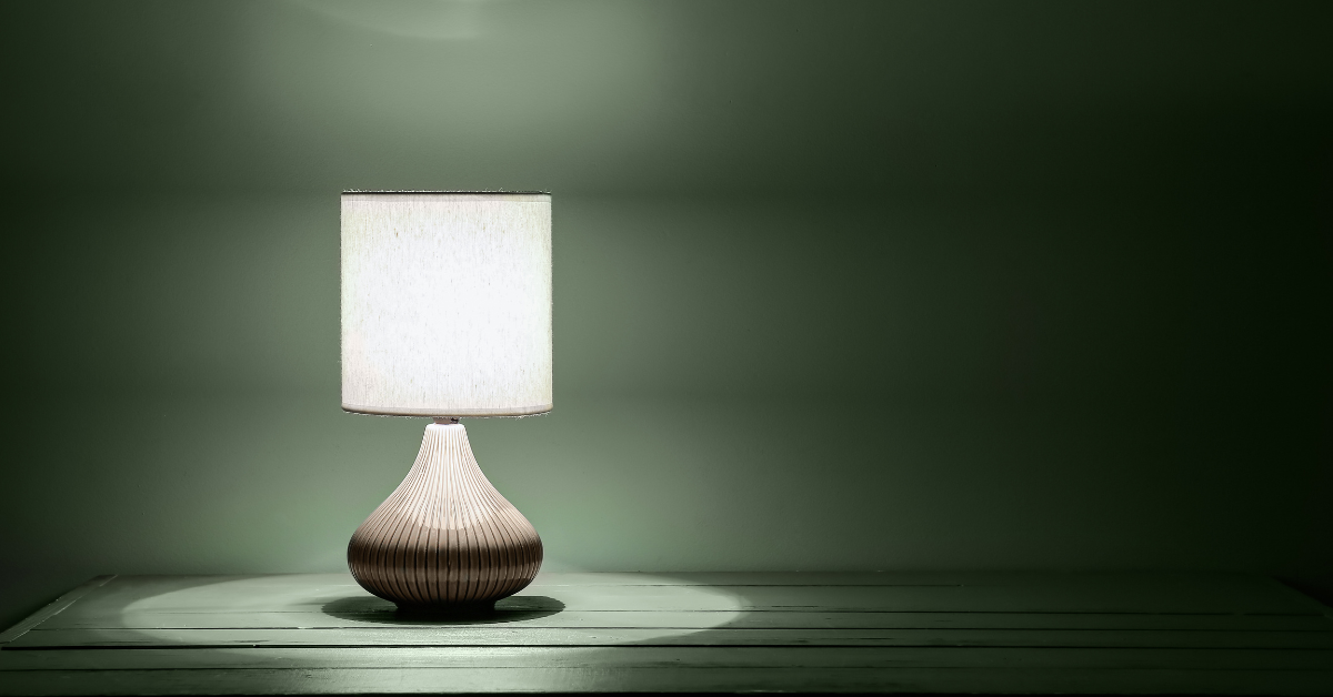 Photograph of a lamp in darkness, surrounded by a green wall