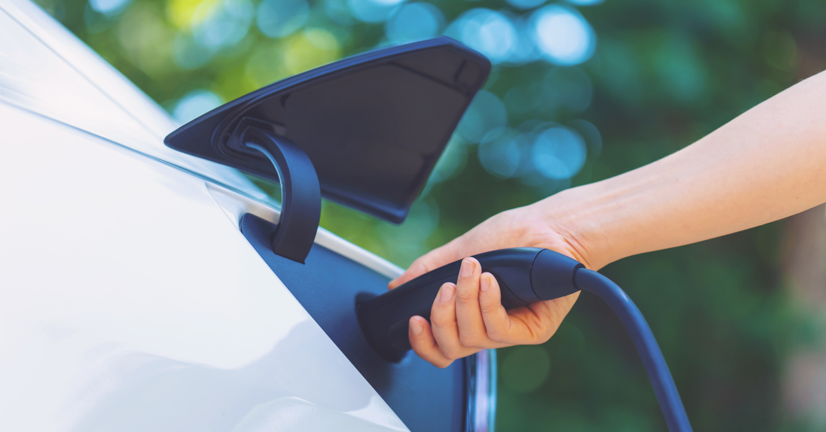 Photo close up of a hand charging an electric vehicle via cable